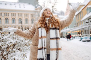 Kıvırcık saçlı kadın karlı bir caddede kış tatilinin tadını çıkarıyor. Kış tatili.
