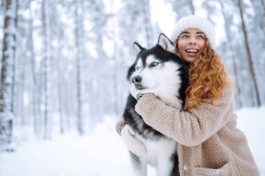 Karda, köpeğiyle oynayan neşeli bir kadın. Arkadaşlık. Evcil köpek konsepti.