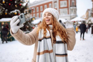 Selfie zamanı. Arka sokaktaki çelenklerde selfie çeken mutlu kadın. Noel tatilleri, dinlenme, blog yazma.