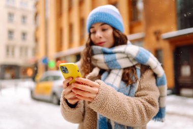 Telefon, Winter Caddesi 'ndeki genç bayanın elinde. Çevrimiçi iletişim. Teknoloji konsepti.