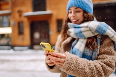 Telefon, Winter Caddesi 'ndeki genç bayanın elinde. Çevrimiçi iletişim. Teknoloji konsepti.