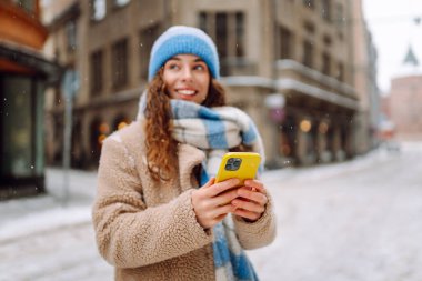 Telefon, Winter Caddesi 'ndeki genç bayanın elinde. Çevrimiçi iletişim. Teknoloji konsepti.