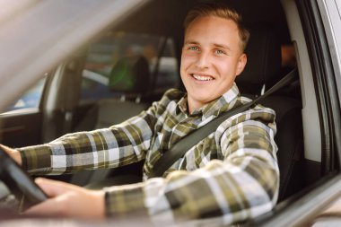 Arabada gülümseyen ve kameraya bakan genç bir adam. Bir araba alıp kiralamak. Araba yolculuğu, yaşam tarzı konsepti..