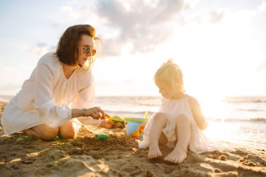 Anne ve kızı sahilde eğleniyor. Oyuncak oynuyor. Aile tatili.