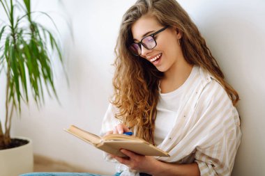 Evde ilginç kitaplar okuyan genç bir kadın. Ev hayatı işte. Rahatla ve rahatla.