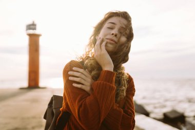 Canlı kırmızı bir deniz fenerinin yanında yürüyen mutlu bir turist. Doğanın tadını çıkarıyorum. Seyahat, hafta sonu, rahatlama ve yaşam tarzı konsepti.