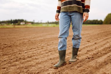 Tarlada yürüyen lastik çizmeli bir çiftçinin bacakları. Bahçe ve ekoloji kavramı.