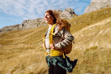 Dağ yamacında gezen genç bir bayan gezgin manzaranın tadını çıkarıyor. Macera aktif. Dağ tırmanışı.