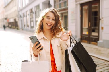 Mutlu Kadın cep telefonunu kullan ve alışveriş torbasını tut. Kara Cuma. Satılık. İnternetten alışveriş.