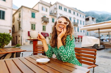 Mutlu kadın turist yaz gezisinde eski kasabada kahve içer. Dinlenme zamanı..