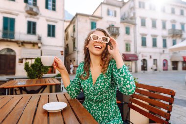 Mutlu kadın turist yaz gezisinde eski kasabada kahve içer. Dinlenme zamanı..