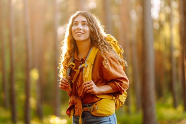 Kalın bir sonbahar ormanında tek başına yürüyüş yapan turist kadın. Tarz sahibi dişi, büyük ağaçlar arasında yol arar. Etkin yaşam biçimi.