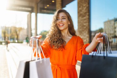 Satılık. Moda alışverişi. Alışveriş yaptıktan sonra alışveriş torbalarıyla şehirde dolaşan mutlu bir kadın. Kara Cuma.