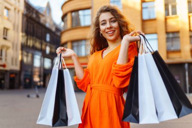 Satılık. Moda alışverişi. Alışveriş yaptıktan sonra alışveriş torbalarıyla şehirde dolaşan mutlu bir kadın. Kara Cuma.