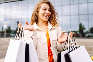 Alışveriş torbalı şık bir kadın şehrin sokaklarında yürüyor. Kara Cuma. Satış, moda, alışverişler.