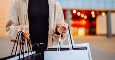 Alışveriş merkezinin yakınında alışveriş torbaları olan genç bir kadın. Kara Cuma. Tüketim, alışverişler, alışveriş, yaşam tarzı.