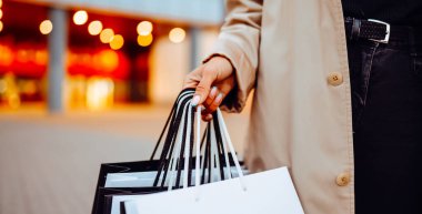 Alışveriş merkezinin yakınında alışveriş torbaları olan genç bir kadın. Kara Cuma. Tüketim, alışverişler, alışveriş, yaşam tarzı.