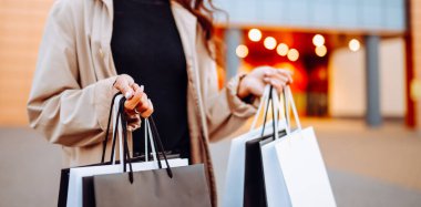 Alışveriş merkezinin yakınında alışveriş torbaları olan genç bir kadın. Kara Cuma. Tüketim, alışverişler, alışveriş, yaşam tarzı.