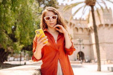 Şehir caddesinde telefonla yürüyen güzel bir kadın. Yaşam tarzı, seyahat, turizm, teknoloji, blog yazma, iletişim kavramı.