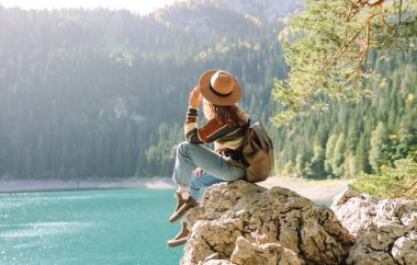 Dişi gezgin dağların arasındaki göl manzarasının tadını çıkarıyor. Sırt çantasıyla yürüyüş. Etkin yaşam biçimi.