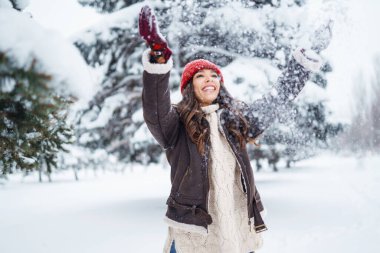 Genç bir kadın soğuk bir günde karla eğleniyor. Kış ormanında bir yürüyüş. Eğlence kavramı, rahatlama..