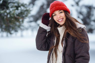 Genç bir kadın soğuk bir günde karla eğleniyor. Kış ormanında bir yürüyüş. Eğlence kavramı, rahatlama..