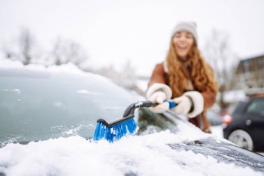 Arabanın ön camından kar temizleyen kadın. Buz kazıyorum. Ulaşım, kış, hava, insan ve araç kavramı.