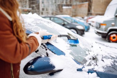 Arabanın ön camından kar temizleyen kadın. Buz kazıyorum. Ulaşım, kış, hava, insan ve araç kavramı.