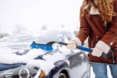 Arabanın ön camından kar temizleyen kadın. Buz kazıyorum. Ulaşım, kış, hava, insan ve araç kavramı.