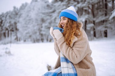 Güzel bir kadın, doğada kışın sıcak bir bardaktan sıcak bir içecek içiyor. Kış ormanı Seyahat, turizm, doğa, aktif yaşam tarzı.