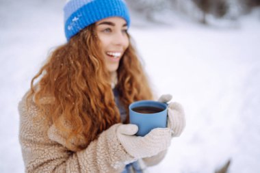 Güzel bir kadın, doğada kışın sıcak bir bardaktan sıcak bir içecek içiyor. Kış ormanı Seyahat, turizm, doğa, aktif yaşam tarzı.