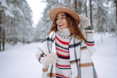 Gülümseyen genç kadın karlı kış parkında kış havasının tadını çıkarıyor. Boho tarzı. Tatiller, dinlenme, seyahat konsepti.
