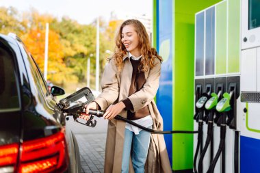 Bir kadın benzin istasyonunda arabasına benzin dolduruyor. Avto gezisi.