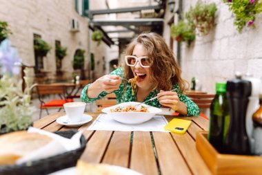 İtalyan makarnası yiyen ve Roma caddesindeki restoranda kahve içen bir kadın. İtalyan gastronomisi ve seyahati kavramı.