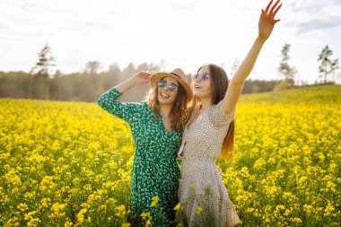 Çiçek açan bir alanda iki güzel kadın. Doğa, tatil, rahatlama ve yaşam tarzı. Yaz manzarası.