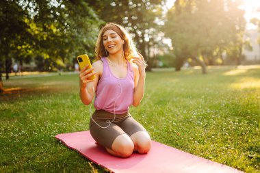 Eşofmanlı genç bayan antrenör halk parkında yoga pozunu değiştiriyor. Yaşam tarzı ve meditasyon konsepti.