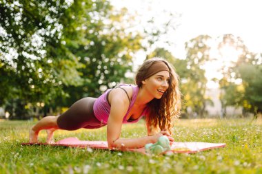 Eşofmanlı genç bayan antrenör halk parkında yoga pozunu değiştiriyor. Yaşam tarzı ve meditasyon konsepti.