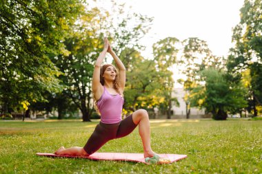 Eşofmanlı genç bayan antrenör halk parkında yoga pozunu değiştiriyor. Yaşam tarzı ve meditasyon konsepti.