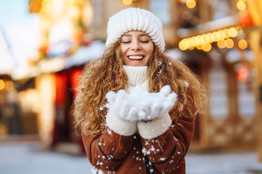 Mutlu kadın güler ve kışın Noel pazarına kar atar. O, güzel kış havasının tadını çıkarıyor. Kış tatili.