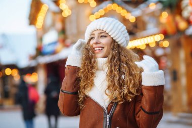 Mutlu kadın güler ve kışın Noel pazarına kar atar. O, güzel kış havasının tadını çıkarıyor. Kış tatili.