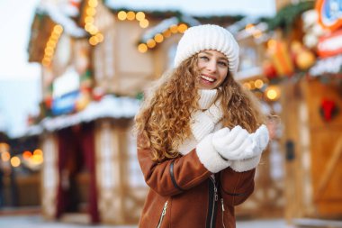 Mutlu kadın güler ve kışın Noel pazarına kar atar. O, güzel kış havasının tadını çıkarıyor. Kış tatili.