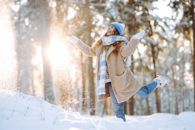 Güneşli bir kış gününde karla oynayan mutlu bir kadının portresi. Eğlence anlayışı, rahatlama. Doğa, tatiller, seyahat kavramı.