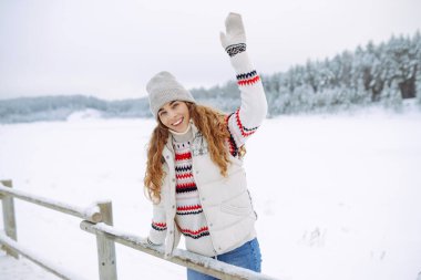 Şapkalı ve eşarplı mutlu kadın kış gününün tadını çıkarıyor. Doğa, tatiller, dinlenme, seyahat konsepti.