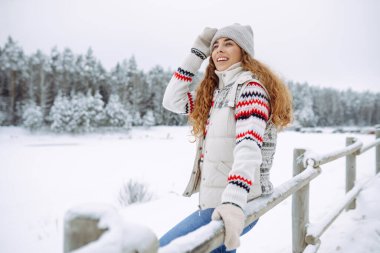 Şapkalı ve eşarplı mutlu kadın kış gününün tadını çıkarıyor. Doğa, tatiller, dinlenme, seyahat konsepti.