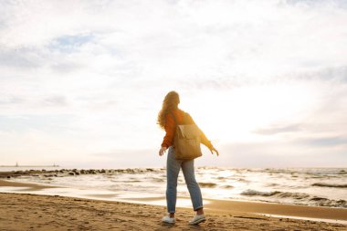 Gün batımında sahilde güzel bir kadının portresi. Soğuk hava. Turist, aktif yaşam tarzı, rahatlama konsepti.