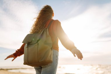 Gün batımında sahilde güzel bir kadının portresi. Soğuk hava. Turist, aktif yaşam tarzı, rahatlama konsepti.