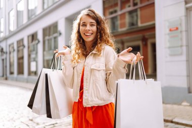 Alışveriş çantalı mutlu kadın şehir sokaklarında yürüyor. Tüketim, moda, alışverişler, alışveriş, yaşam tarzı konsepti.