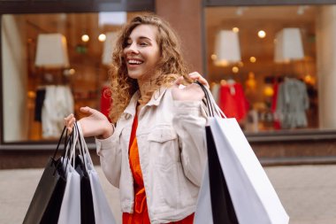 Alışveriş çantalı mutlu kadın şehir sokaklarında yürüyor. Tüketim, moda, alışverişler, alışveriş, yaşam tarzı konsepti.