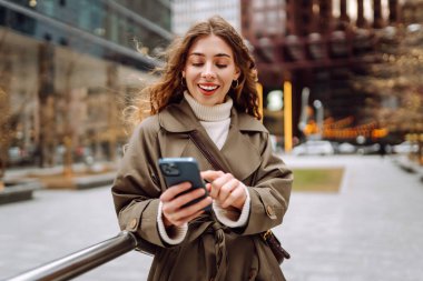 Sokakta telefonu kullanan güzel bir kadın. Tatil kavramı, blog yazma, teknoloji, hafta sonu.