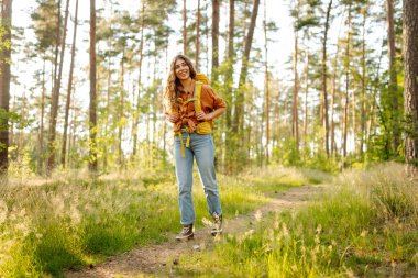 Dişi sırt çantalı turist ağaçlara bakıyor ve doğa manzarasının tadını çıkarıyor. Aktif yaşam tarzı. Yürüyüş.